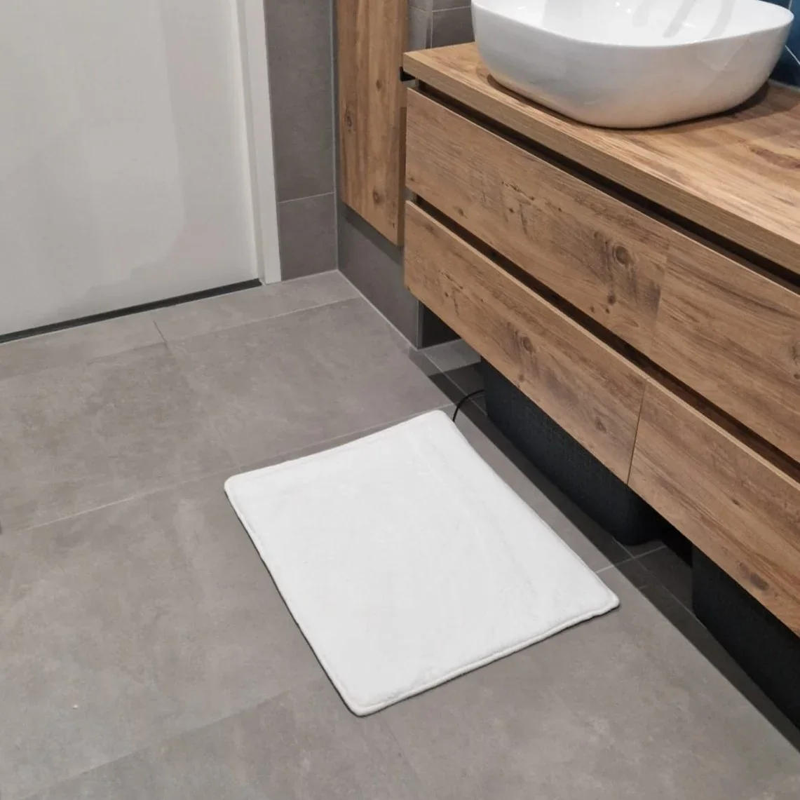 Warme voeten op de witte verwarmde badmat in de badkamer